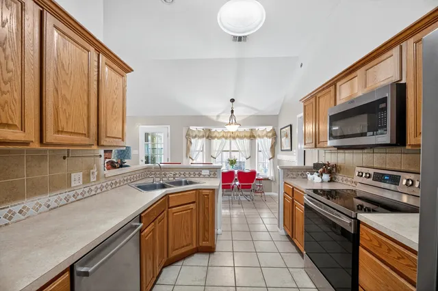 a kitchen with stainless steel appliances a sink dishwasher stove top oven refrigerator and cabinets