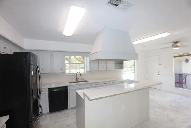 a large kitchen with a refrigerator a sink dishwasher with a stove and white cabinets