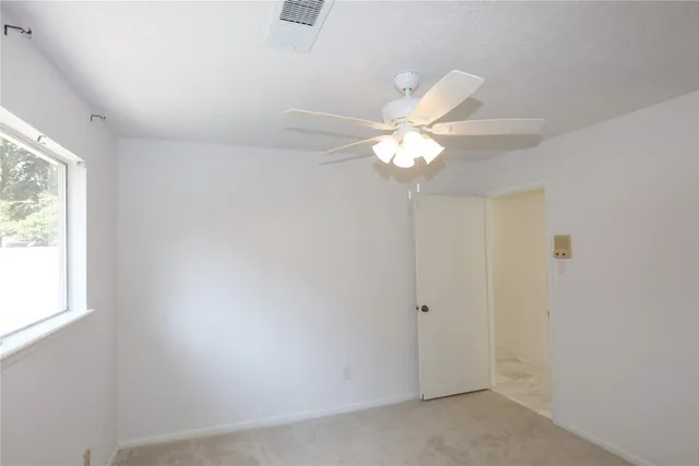 an empty room with a window and a fan