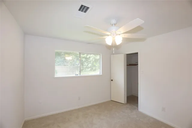 an empty room with a window and a fan