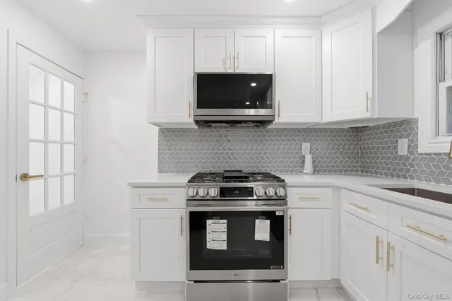 a kitchen with stainless steel appliances a stove a microwave and white cabinets