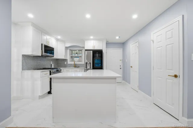 a large kitchen with kitchen island a sink stainless steel appliances and cabinets