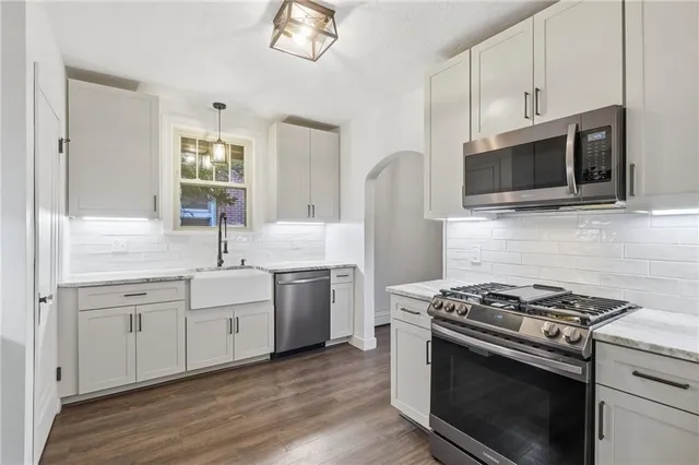 a kitchen with stainless steel appliances white cabinets a stove top oven and sink
