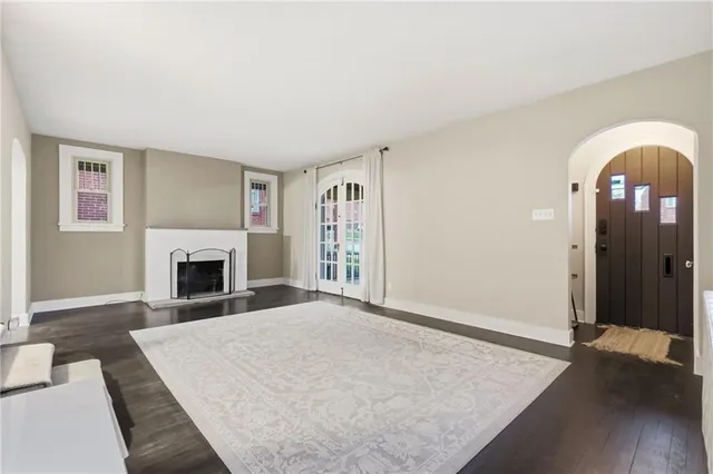 an empty room with windows fireplace and wooden floor