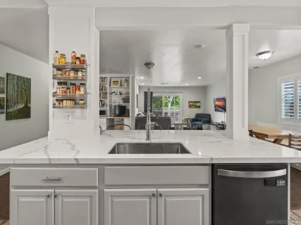 a view with granite countertop a sink white cabinets and a wooden floor