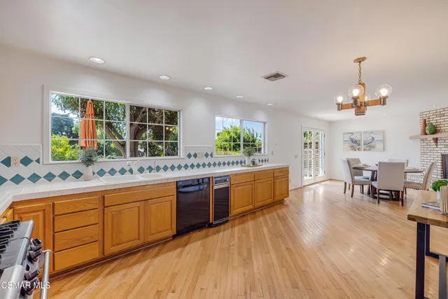 a large kitchen with stainless steel appliances a large counter top a stove and a wooden floors