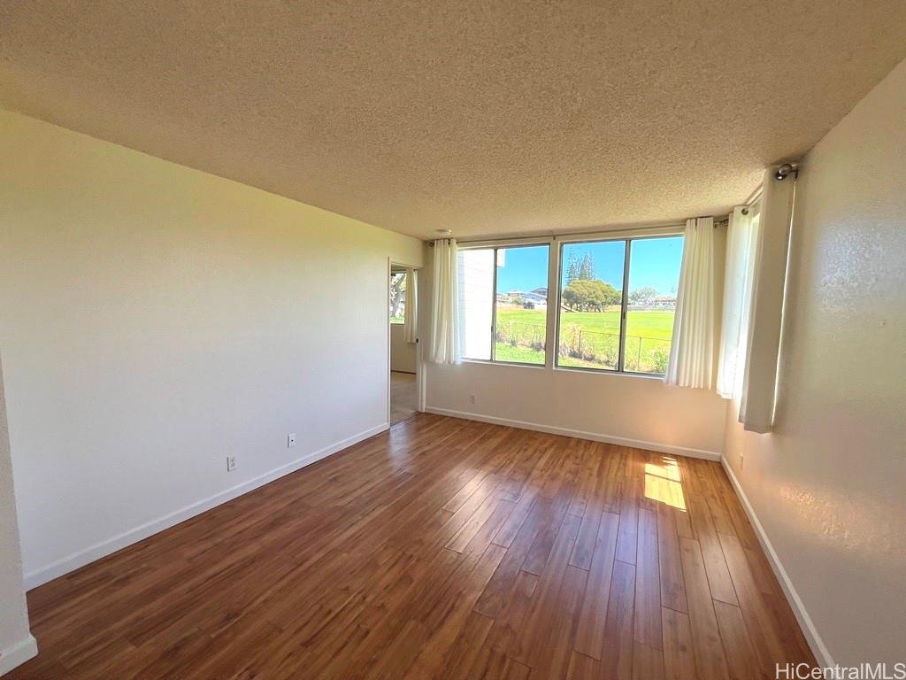 95-670 Hanile Street, Unit A102 Mililani, HI 96789 - Photo 3 of 13 an empty room with wooden floor and windows