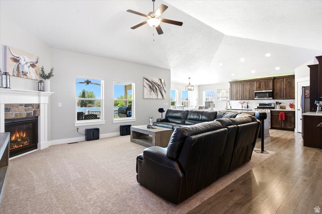 2973 West Red Sand Rd Haven Ogden, UT 84401 - Photo 13 of 30 Spacious living area featuring vaulted ceilings, a stone-faced fireplace with a white mantel, and light carpeting