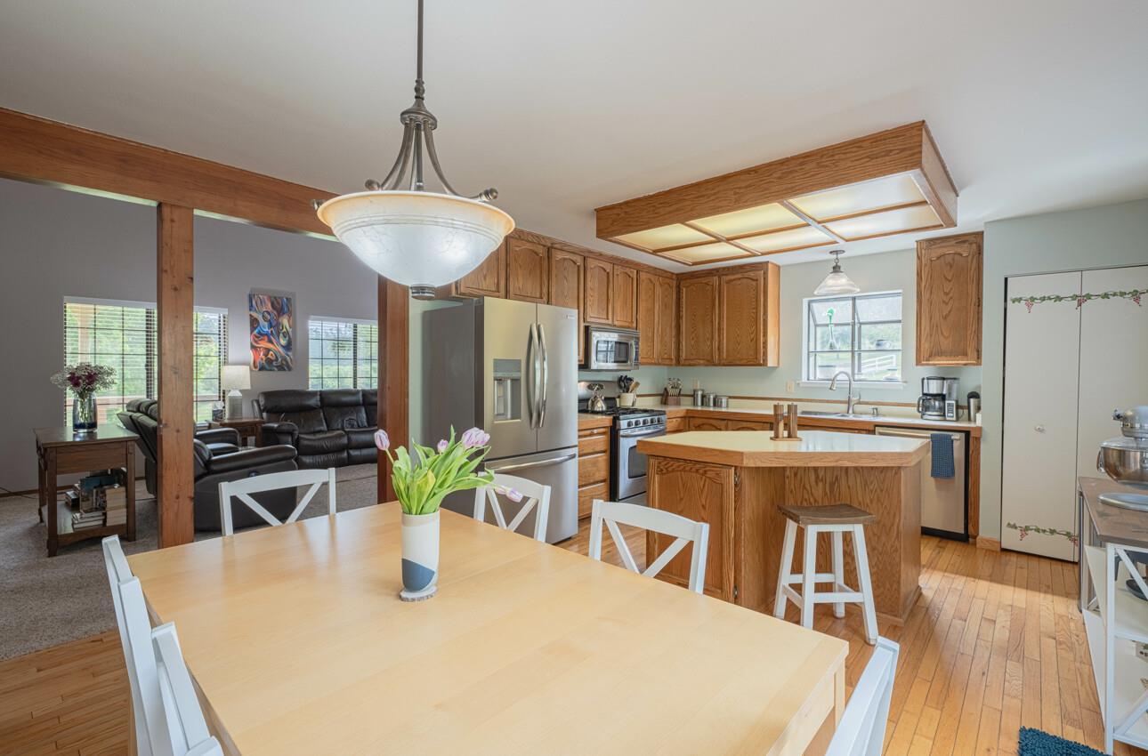 744 Seely Avenue Aromas, CA 95004 - Photo 25 of 55 a kitchen with stainless steel appliances granite countertop a stove a sink a refrigerator a dining table and chairs with wooden floor