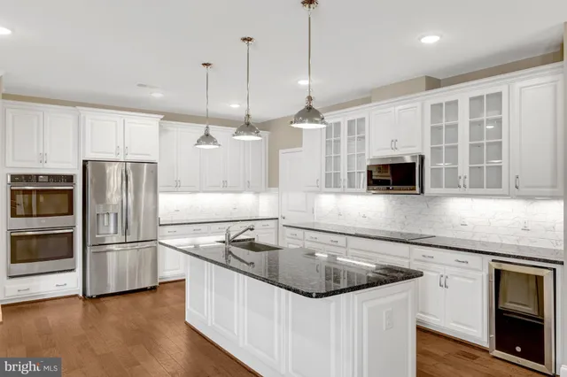a kitchen with stainless steel appliances granite countertop a sink a microwave a refrigerator and white cabinets