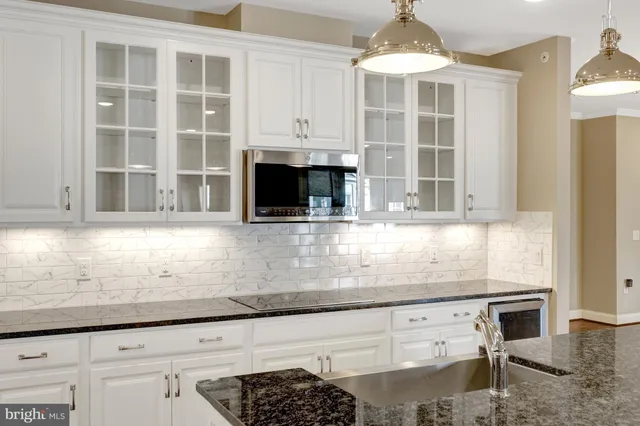 a kitchen with granite countertop a stove and a white cabinets