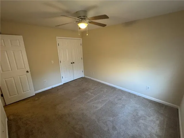 an empty room with a chandelier fan and a fireplace