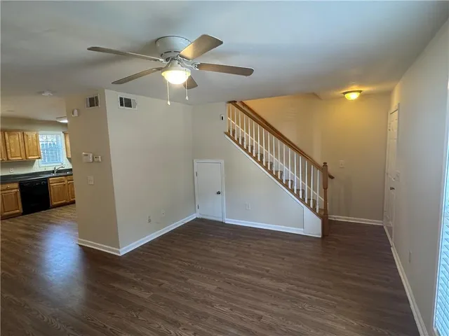 a view of a livingroom with wooden floor a ceiling fan and staircase