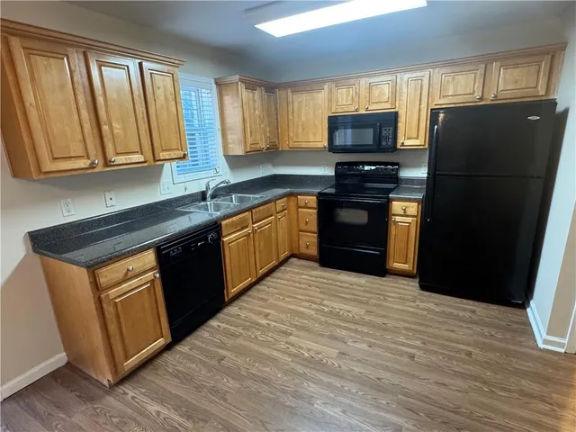 a kitchen with granite countertop wooden cabinets a refrigerator stove top oven and sink