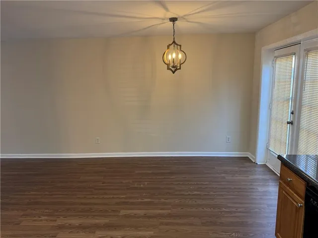 a view of an empty room with wooden floor and window
