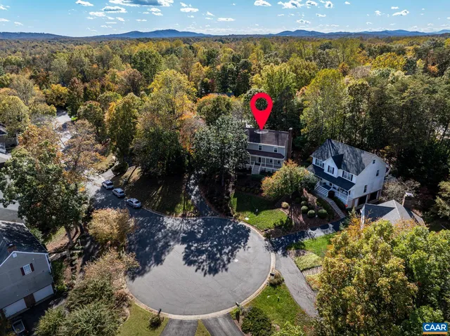 a view of a brick wall with plants and large trees