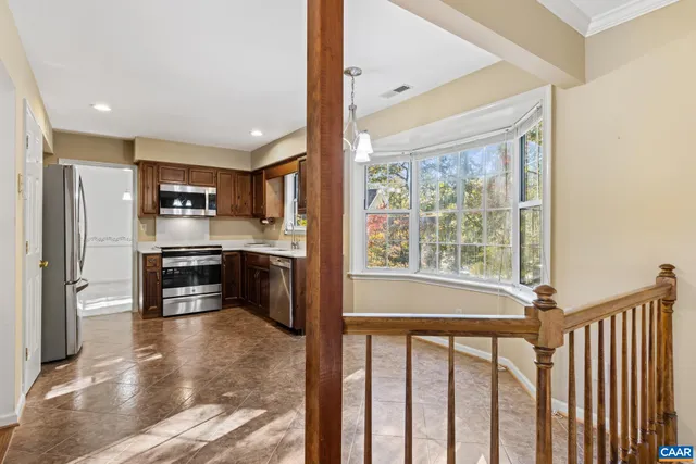 a large kitchen with kitchen island a large window a sink and stainless steel appliances