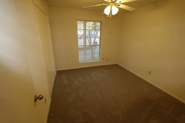 an empty room with a window and a fan