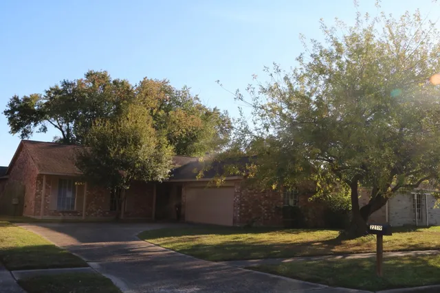 a view of a house with a yard and a large tree