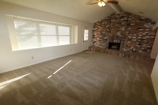 en empty room with windows and fireplace