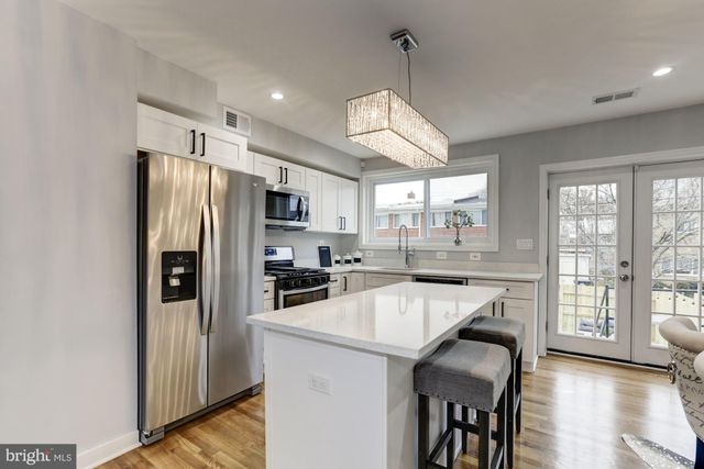 a kitchen with stainless steel appliances granite countertop a refrigerator a sink a stove a dining table and chairs