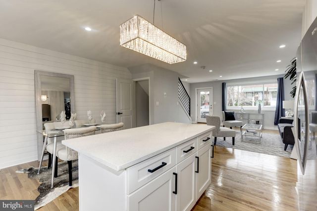 a large white kitchen with a large island oven a stove a sink a dining table and chairs