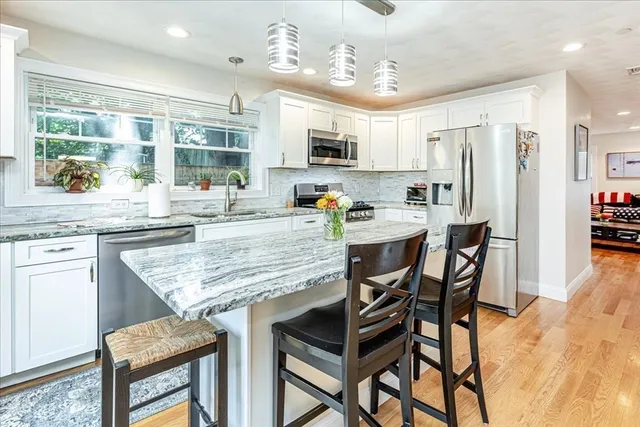 a kitchen with stainless steel appliances kitchen island granite countertop a table chairs sink and cabinets