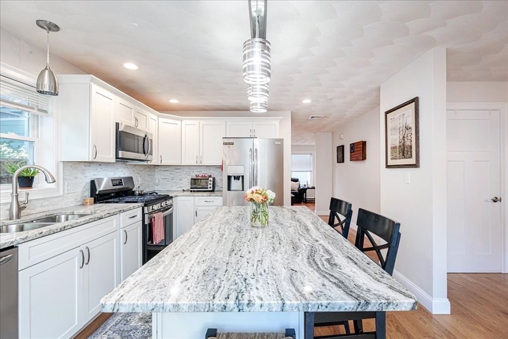 105 Green Street, Unit 4 Marblehead, MA 01945 - Photo 4 of 30 a large kitchen with kitchen island a stove a sink a dining table and chairs
