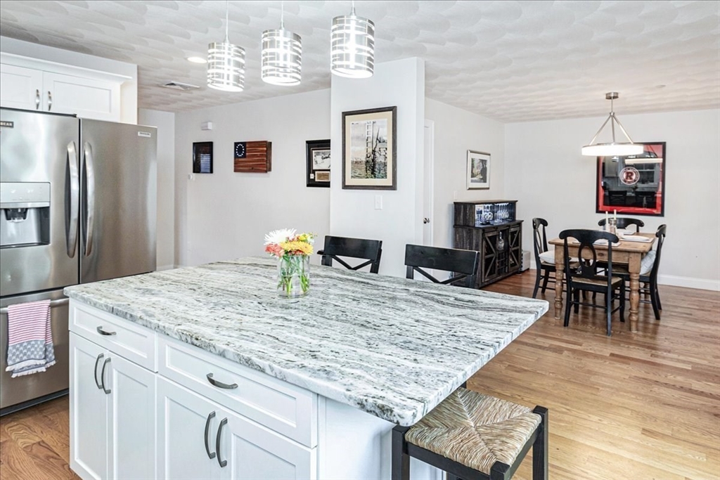 105 Green Street, Unit 4 Marblehead, MA 01945 - Photo 5 of 30 a kitchen with stainless steel appliances granite countertop dining table chairs and wooden floor