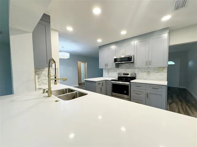 a kitchen with granite countertop a sink stove and refrigerator