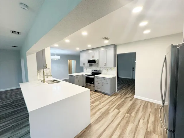 a large kitchen with a lot of counter top space and wooden floor