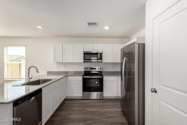 a kitchen with stainless steel appliances granite countertop a refrigerator and a sink