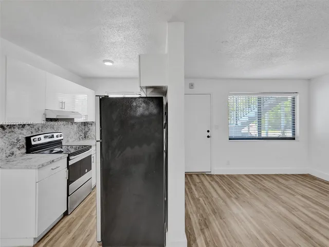 a kitchen with a refrigerator stove and white cabinets