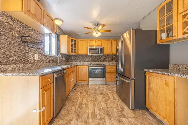 a kitchen with stainless steel appliances granite countertop a refrigerator a stove and a sink