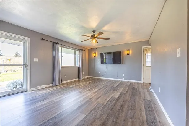 a view of an empty room with a window and wooden floor