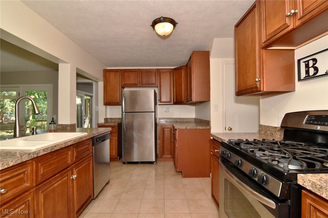 3679 Fenley Road Cleveland Heights, OH 44121 - Photo 13 of 45 Kitchen featuring appliances with stainless steel finishes, brown cabinets, light tile patterned flooring, a textured ceiling, and light countertops