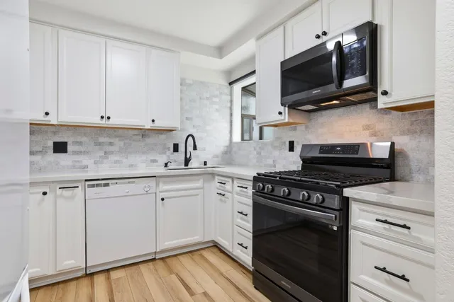 a kitchen with cabinets stainless steel appliances and wooden floor