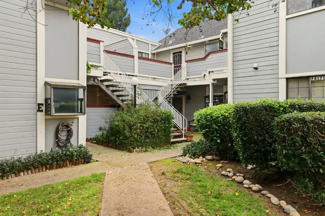 a view of a white house with a yard and potted plants