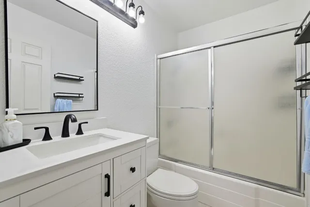 a bathroom with a sink a mirror a toilet and shower