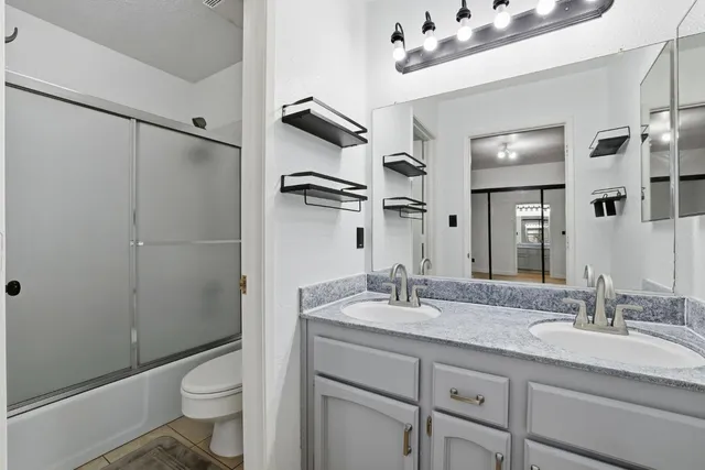 a bathroom with a granite countertop sink toilet mirror and shower