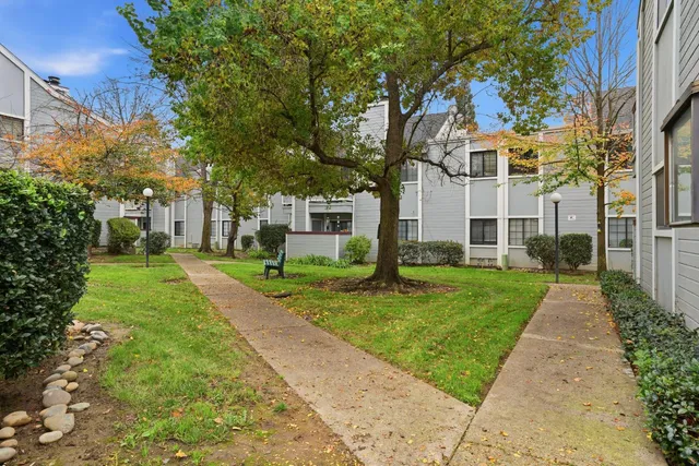 a view of a white house next to a yard with big trees