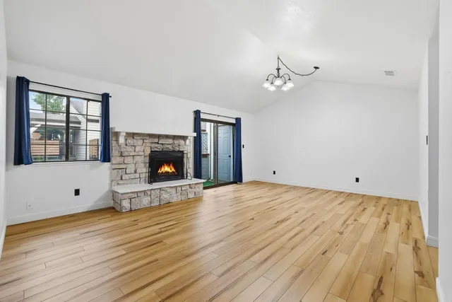 a view of an empty room with wooden floor fireplace and a window