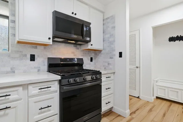 a kitchen with white cabinets stainless steel appliances and wooden floor