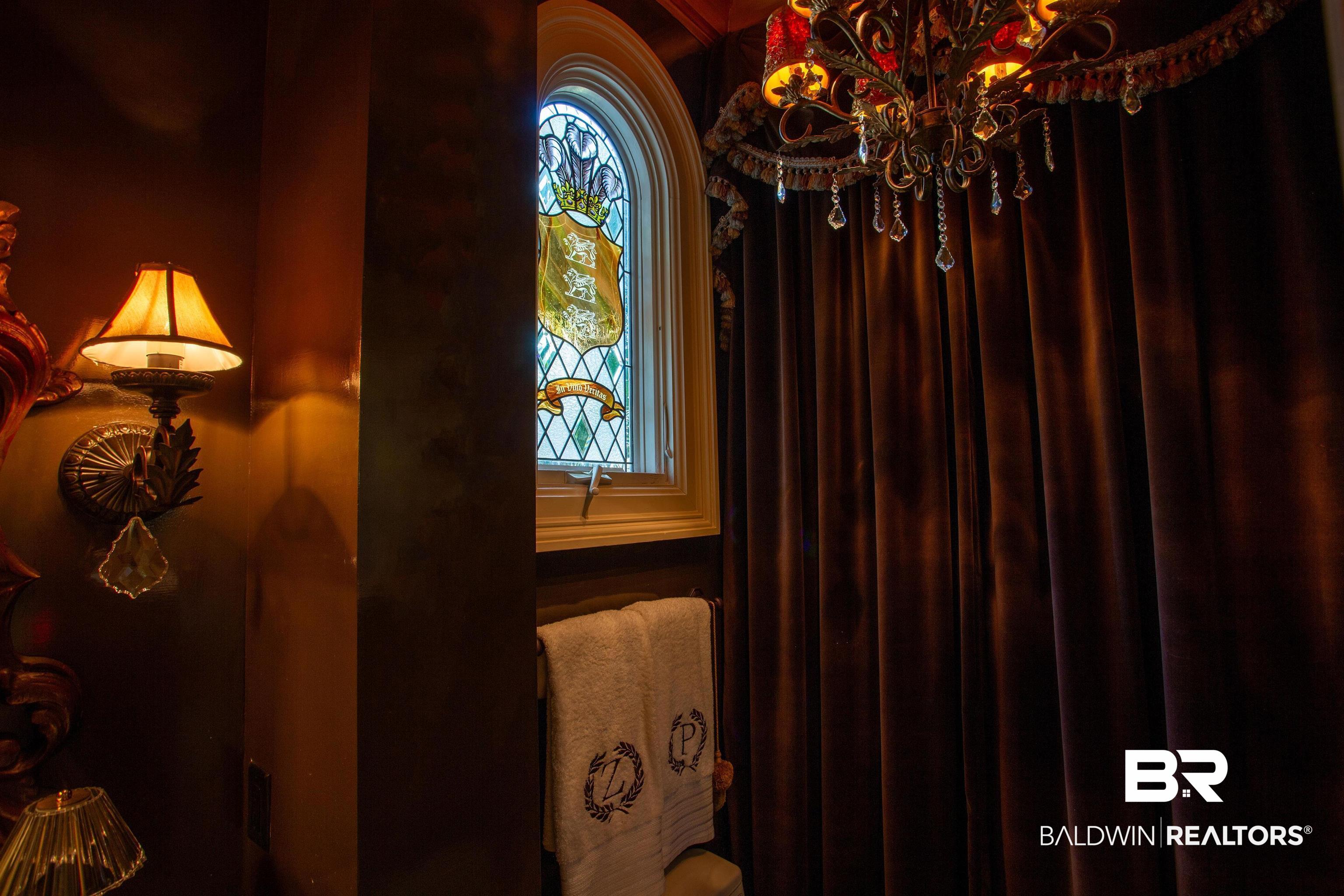 150 Austill Avenue Mobile, AL 36608 - Photo 31 of 39 Stained glass arched window with decorative trim, complemented by a crystal-adorned chandelier and rich velvet drapery