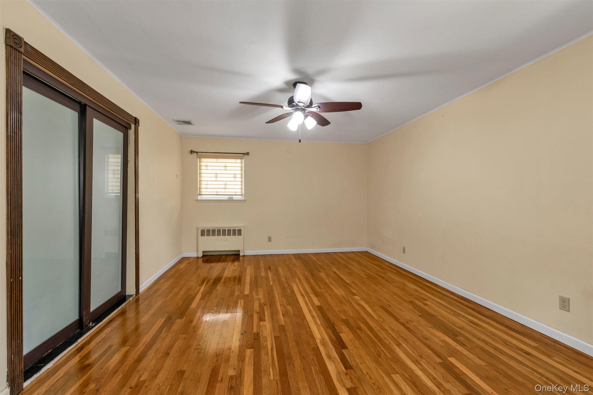 830 Pepperidge Road Westbury, NY 11590 - Photo 13 of 23 a view of a room with wooden floor and a ceiling fan