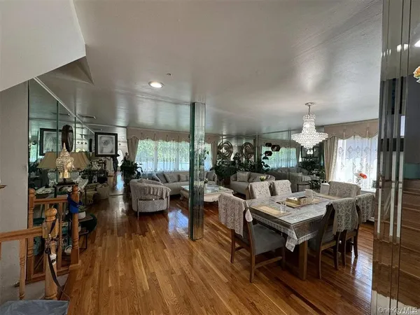 a living room with furniture dining table a large window and wooden floor