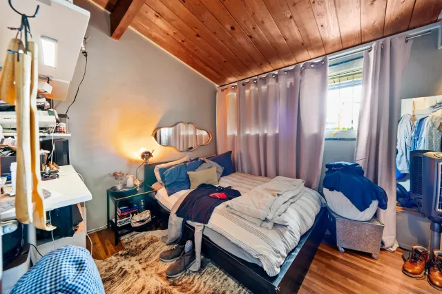 a bedroom with a bed and wooden floor