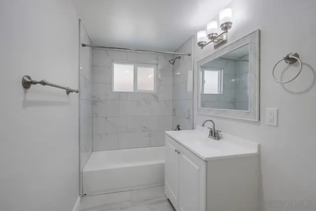 a bathroom with a bathtub shower sink and mirror