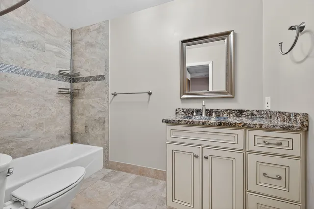 a bathroom with a granite countertop toilet sink and mirror