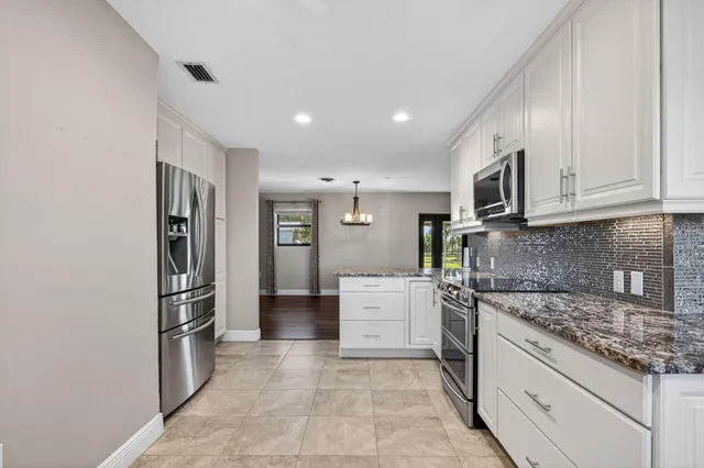 a kitchen with stainless steel appliances granite countertop a refrigerator and a stove top oven